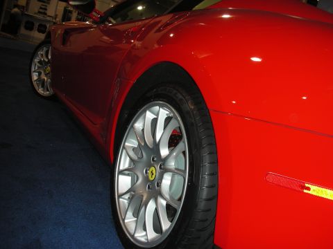 1998 Ford Crown Victoria - Low side view of a red sports car showing its rear quarter, silver multi-spoke wheel with prancing-horse cap and red caliper.