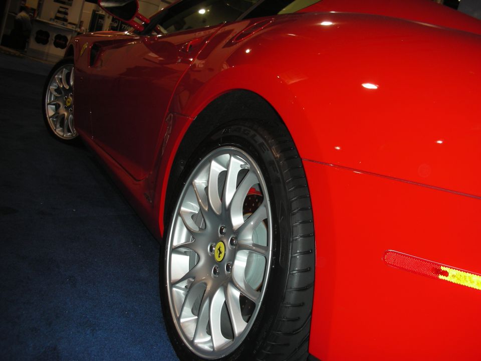 Red sports car body with silver multi-spoke wheel and red caliper