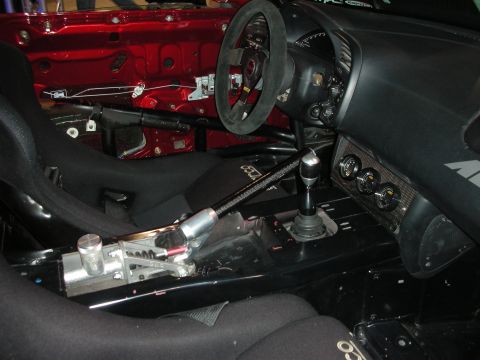 1998 Ford Crown Victoria - gutted race-car interior showing a suede steering wheel, bucket seats, sequential shifter and exposed red bodywork.