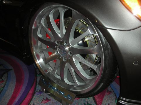 1998 Ford Crown Victoria - Close-up of a polished multi-spoke wheel and red-painted brake caliper on a dark gray show car.