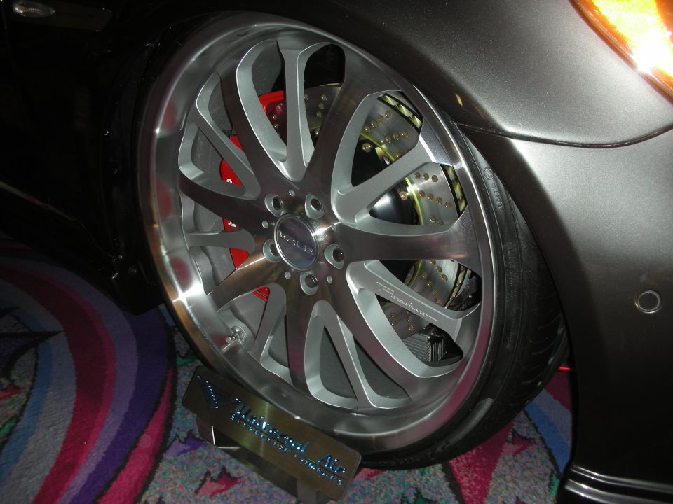 Close-up of chrome multi-spoke wheel with red brake caliper on gray car