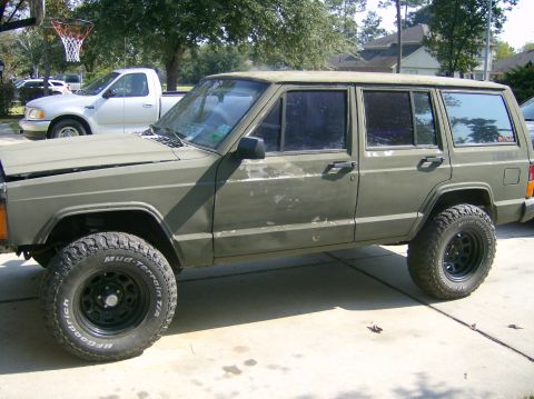 1993 Jeep Cherokee - Side view of a 1993 Jeep Cherokee, parked outdoors with a white pickup truck visible in the background.