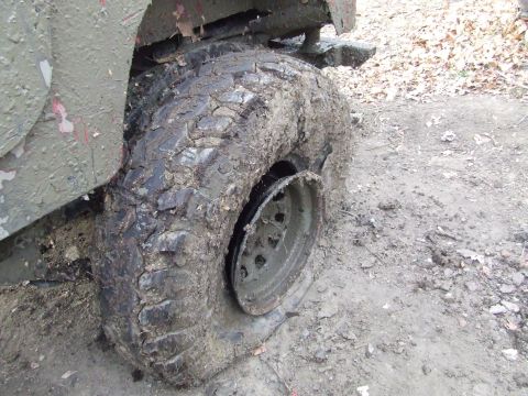 1990 Ford Bronco - A vehicle's tire is heavily caked in mud, with the rim detached, suggesting it is stuck.