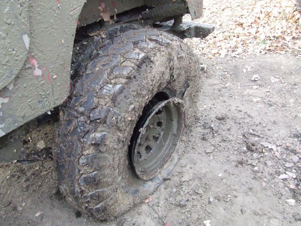 Mud-caked tire with a detached rim on a dirt road