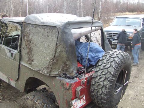 1990 Ford Bronco - A muddy Jeep Wrangler sits in the foreground, with a 1990 Ford Bronco and two people visible behind it.