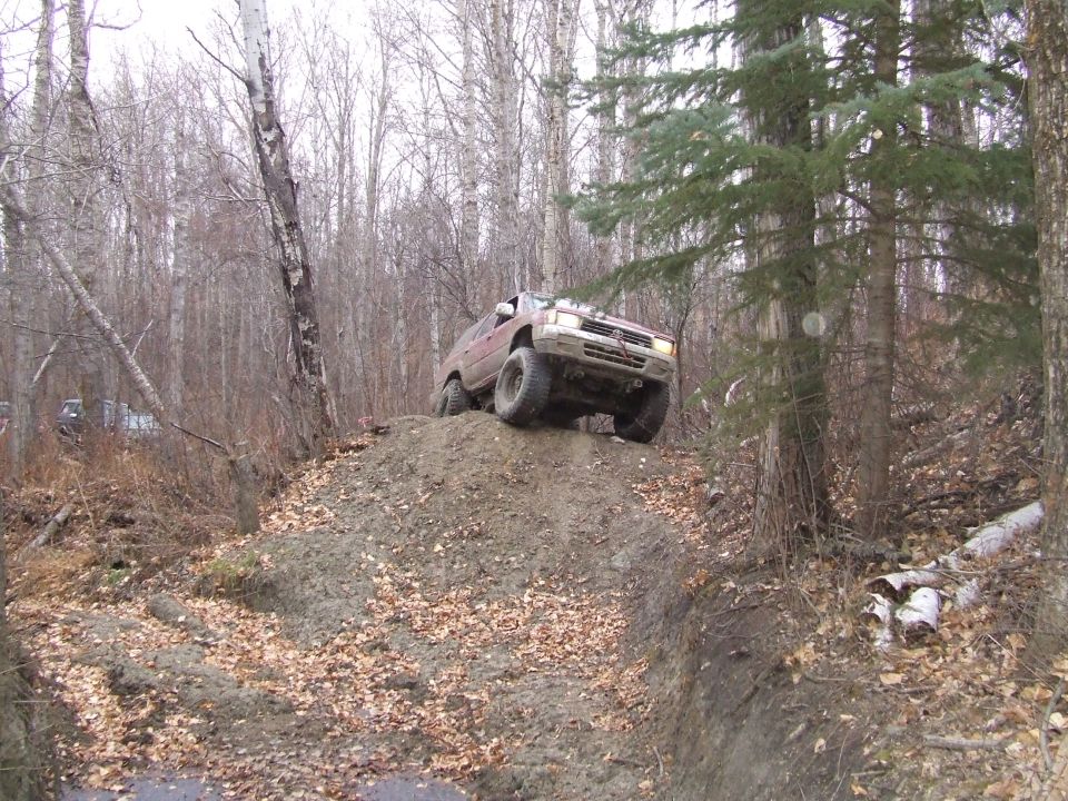 Red 1990 Ford Bronco climbing a dirt hill off-road