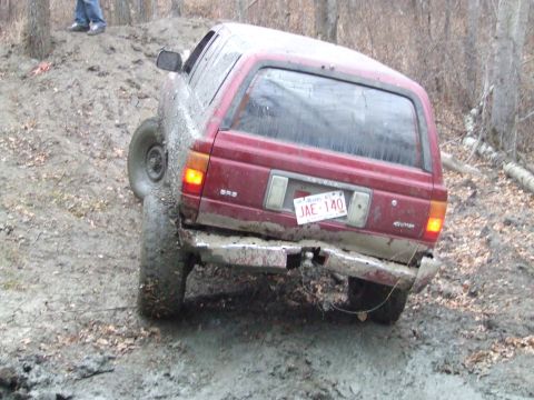 1990 Ford Bronco - A red Toyota 4Runner is stuck in the mud on a hill, its rear end visible.