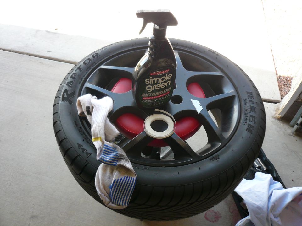 Black car wheel with a bottle of Simple Green cleaner and a sock on it