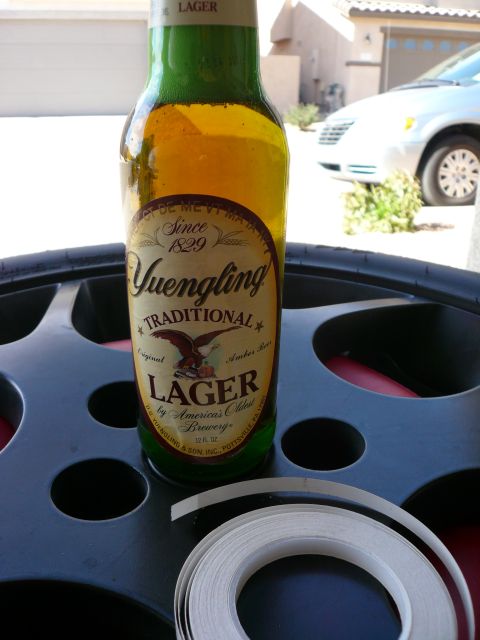 1996 Ford Probe - A silver minivan is visible in the background behind a bottle of Yuengling Traditional Lager and a roll of tape.