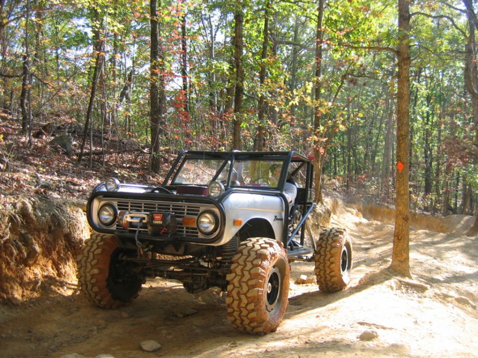 Silver off-road vehicle with roll cage and large tires on a dirt trail