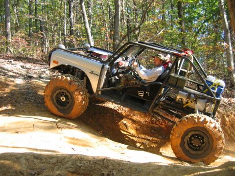1992 Ford Mustang - Off-road vehicle navigates a steep dirt trail surrounded by trees.