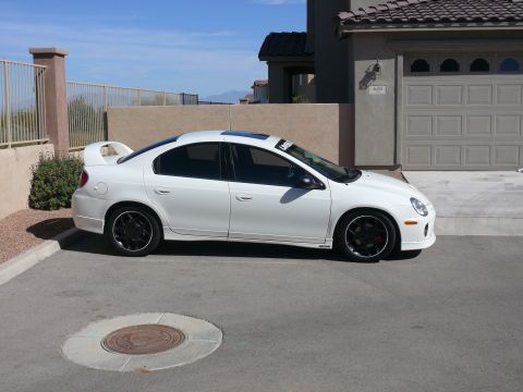 1996 Ford Probe - A white sedan with a prominent rear spoiler and black wheels is parked in front of a garage.