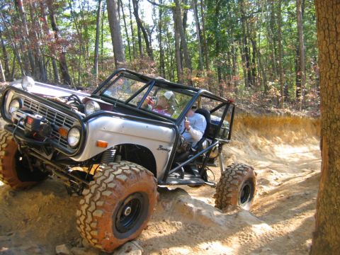 1992 Ford Mustang - A modified off-road vehicle navigates a challenging dirt trail through a wooded area.