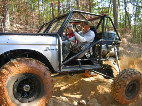 1992 Ford Mustang - Modified off-road vehicle navigating a rocky, wooded trail.