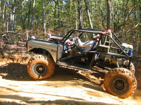 1992 Ford Mustang - Modified off-road vehicle navigates a dirt trail through a wooded area.