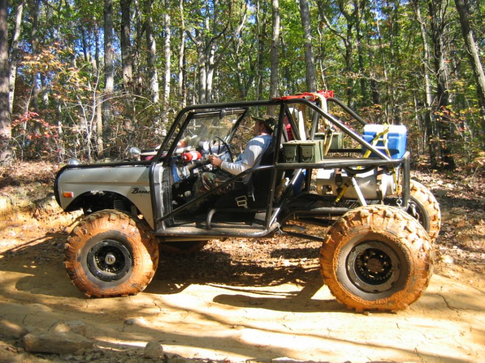 Modified off-road vehicle with roll cage and large tires on a dirt trail