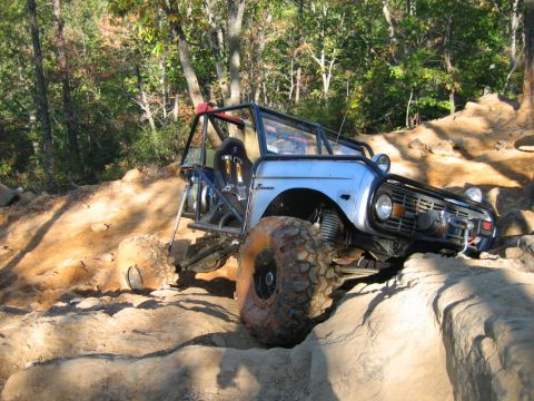 1992 Ford Mustang - Modified light blue Bronco navigates challenging rocky terrain with large off-road tires and a protective roll cage.