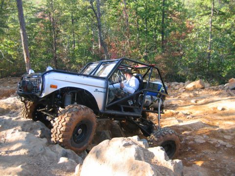 1992 Ford Mustang - This modified off-road vehicle navigates a challenging rocky trail, its robust suspension and protective roll cage.