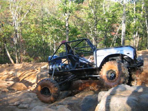 1992 Ford Mustang - Modified buggy tackling a challenging rocky trail with large tires.