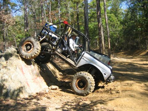 1992 Ford Mustang - This modified off-road vehicle navigates a challenging rocky incline on a dirt trail.
