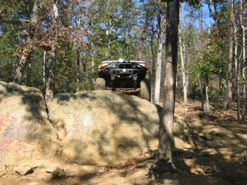 1992 Ford Mustang - A modified off-road vehicle navigates a rocky terrain on a wooded trail.