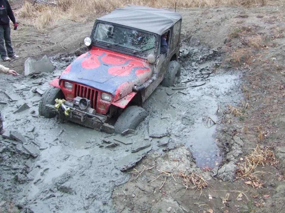 Red Jeep Wrangler stuck in mud with flames painted on hood