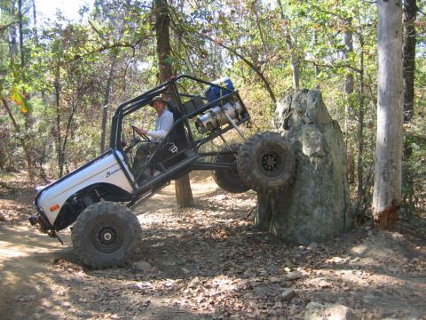 1992 Ford Mustang - Custom off-road buggy navigates a challenging rock obstacle on a wooded trail.