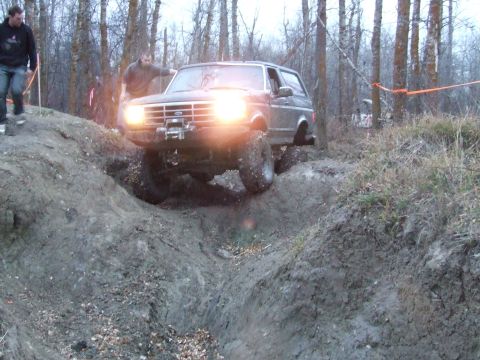 1990 Ford Bronco - A Ford Bronco navigates a challenging off-road course in a wooded area.
