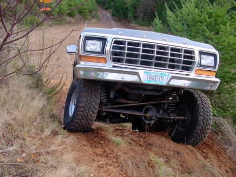 1979 Ford Bronco - A lifted 1979 Ford Bronco navigates an off-road trail with a clear view of its front grille and suspension.
