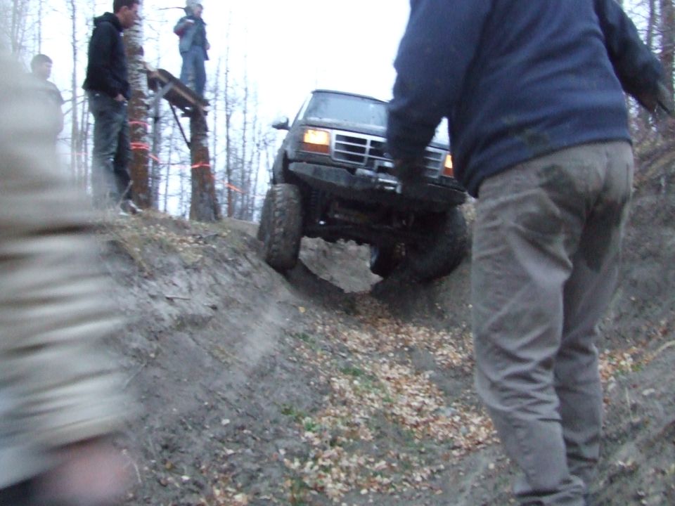 1990 Ford Bronco climbing a muddy hill, front grille visible