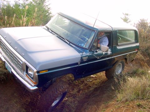 1979 Ford Bronco - A 1979 Ford Bronco navigates an off-road trail, with its driver visible behind the wheel.