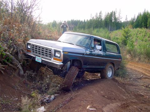 1979 Ford Bronco - Ford Bronco navigates challenging off-road terrain with one wheel lifted.