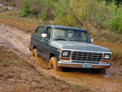 1979 Ford Bronco - This Ford Bronco is navigating a challenging muddy terrain, with its tires deep in the muck.