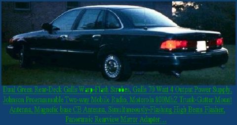 1996 Ford Crown Victoria - Rear view of a dark sedan, likely a police interceptor, with emergency lights and equipment.