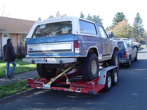 1978 Ford Bronco - A blue and white 1978 Ford Bronco is loaded onto a U-Haul trailer, with a blue pickup truck following behind.