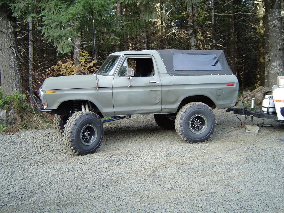 Lifted 1978 Ford Bronco, side view, green with soft top, towing a trailer
