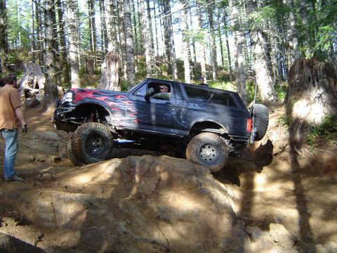 1978 Ford Bronco - A modified Ford Bronco navigates a rocky off-road course in a forest setting.