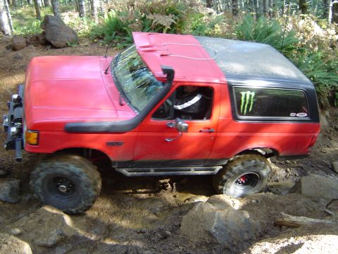 1978 Ford Bronco - This red SUV, likely a 1992 Ford Bronco, navigates a challenging off-road course.