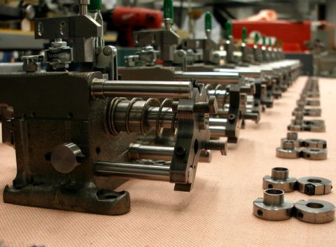 1996 Ford Bronco - Multiple machine components and small metal parts are arranged in a factory setting.