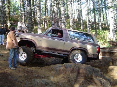 1978 Ford Bronco - A lifted Ford Bronco tackles an off-road trail in a wooded area.