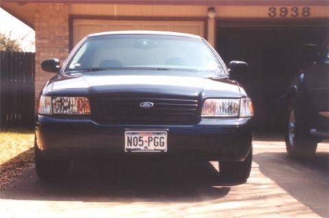 2002 Ford Crown Victoria - The front of a Ford Crown Victoria is shown parked in front of a garage with the number 3938 above the door.