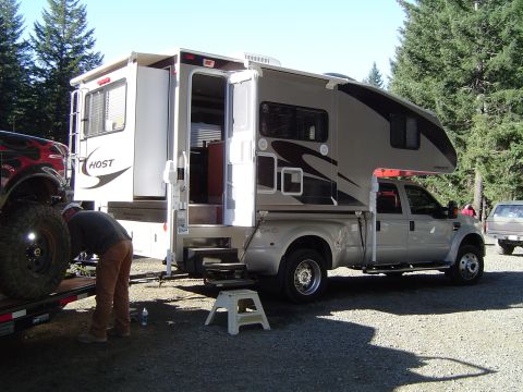 1978 Ford Bronco - A Ford F-series truck is fitted with a Host camper shell, parked outdoors with trees in the background.