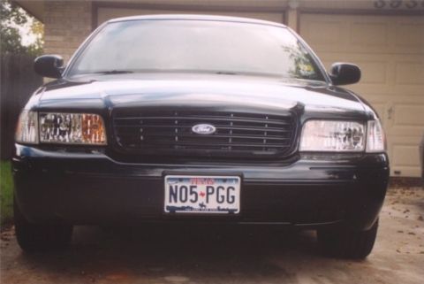 2002 Ford Crown Victoria - Front view of a black 2002 Ford Crown Victoria parked in front of a garage.