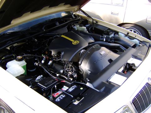 1996 Mercury Grand Marquis - Engine bay of a 1996 Mercury Grand Marquis, the V8 engine and a distinctive yellow-striped cover.