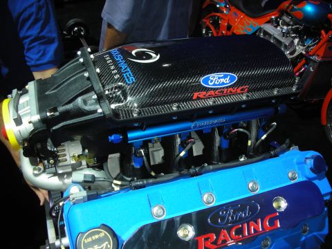 1998 Ford Crown Victoria - Two blue Ford Racing engines with carbon-fiber intake covers displayed close together at an indoor event.