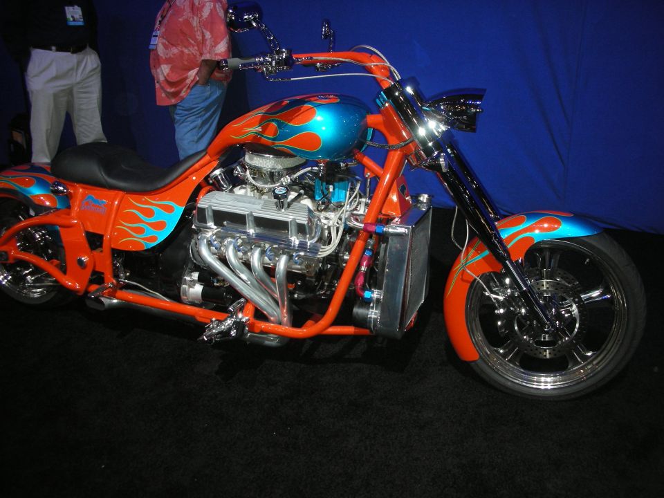 Orange flame-painted custom V-twin chopper motorcycle against blue backdrop