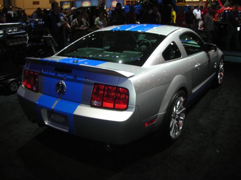 Rear three-quarter of silver Shelby Mustang with blue stripes at auto show