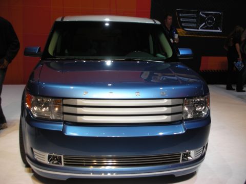 Front view of blue Ford Flex boxy crossover at auto show with crowd