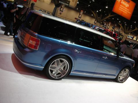 Blue Ford Flex on display at an indoor auto show with chrome wheels