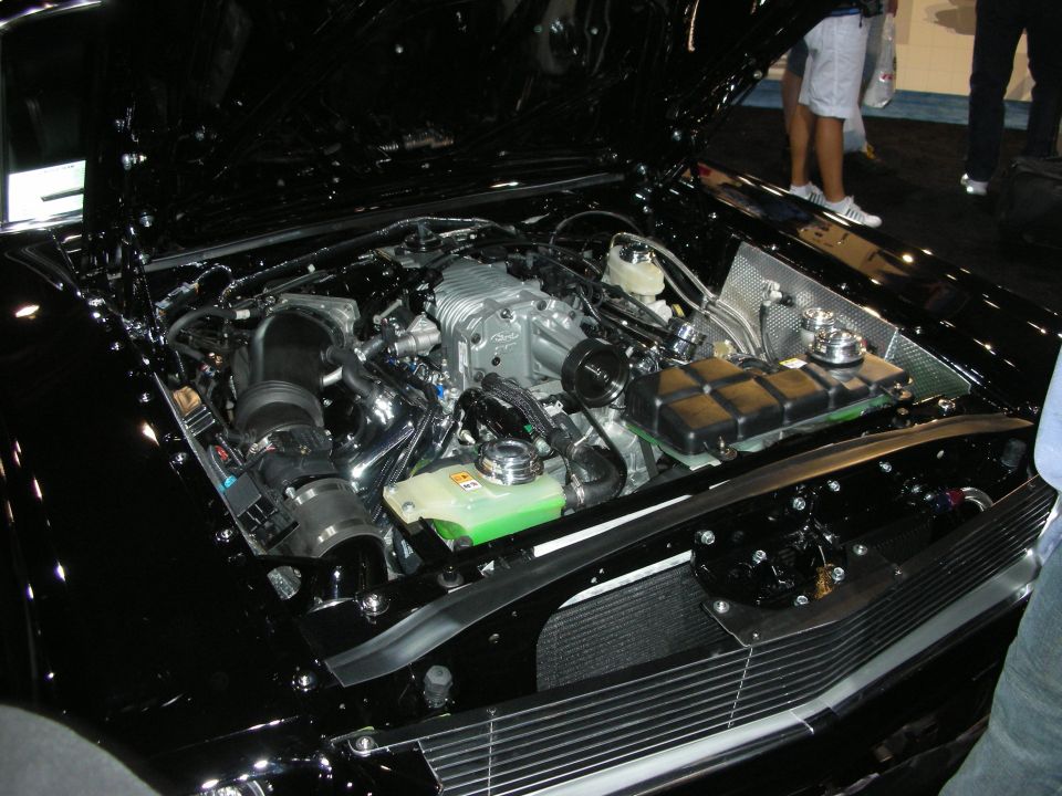 Detailed engine bay of a black car with a polished supercharged V8